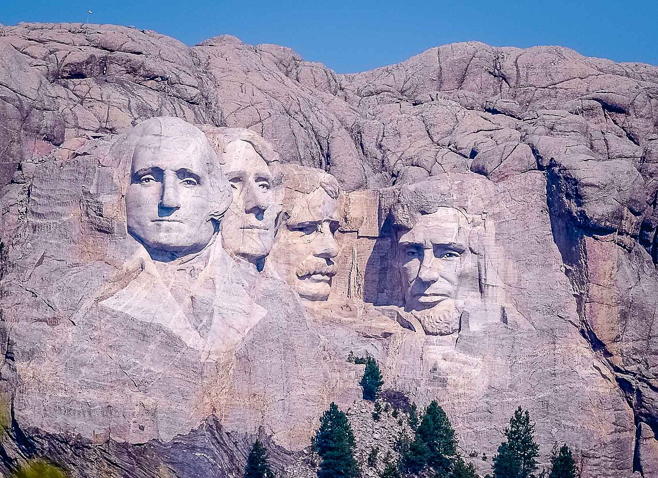 Four huge presidents' faces carved into a mountain, seen from far away.