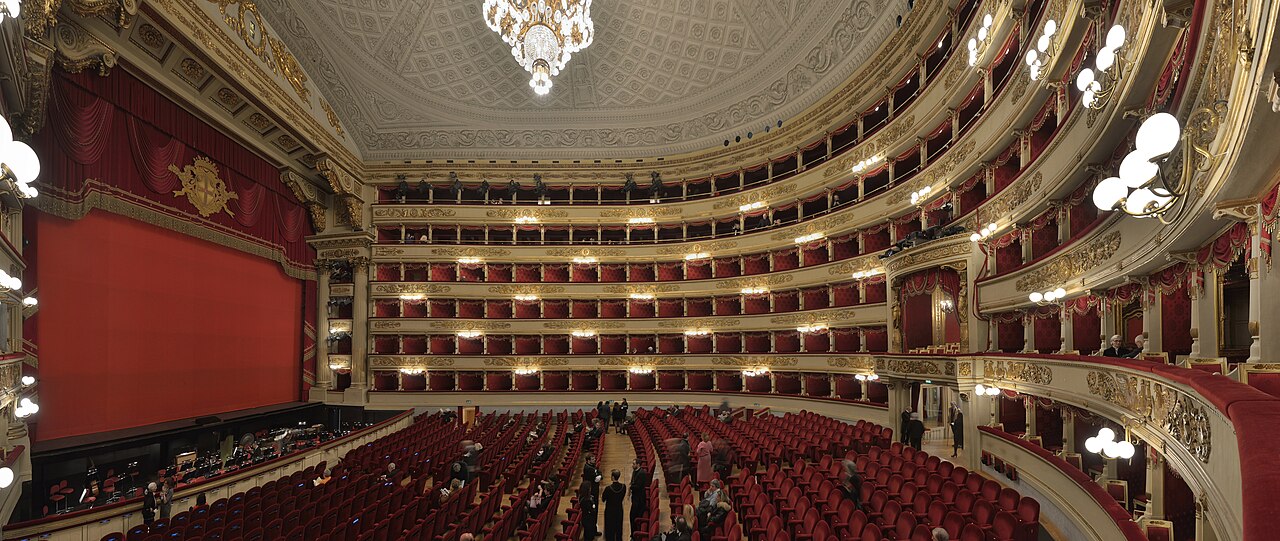 The fancy inside of a famous opera house with lots of red seats.