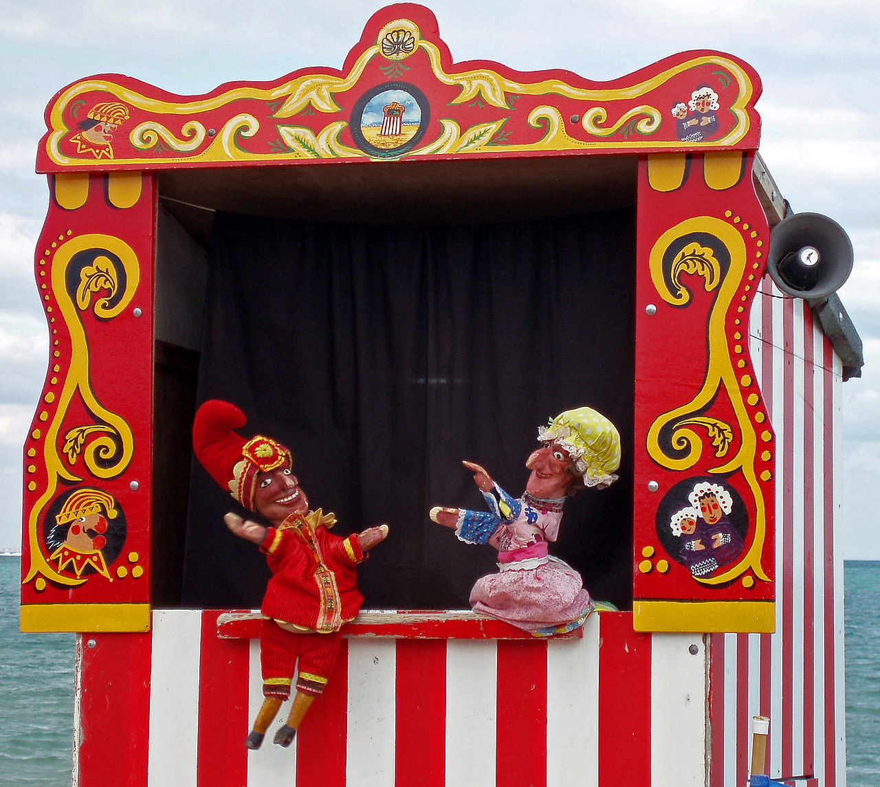 A tall, striped puppet booth where hand puppets put on a show.