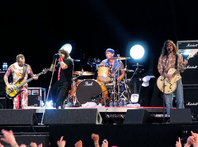 A rock band playing loud music together on stage at a festival.