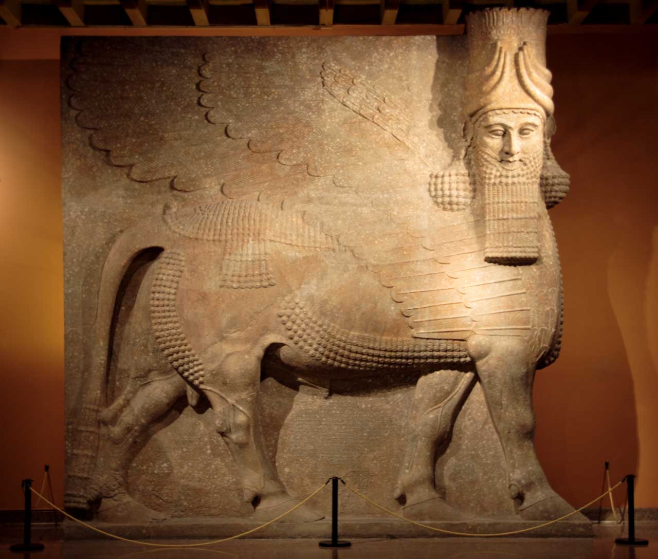 A giant stone statue with a human head, bull body, and wings.