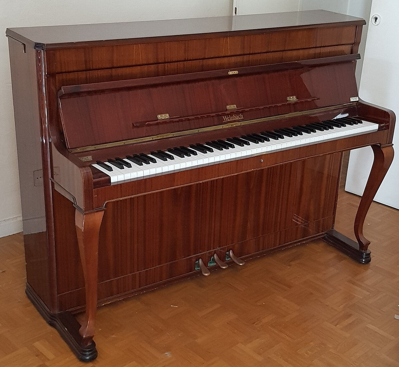 A tall upright piano ready for someone to play a song.