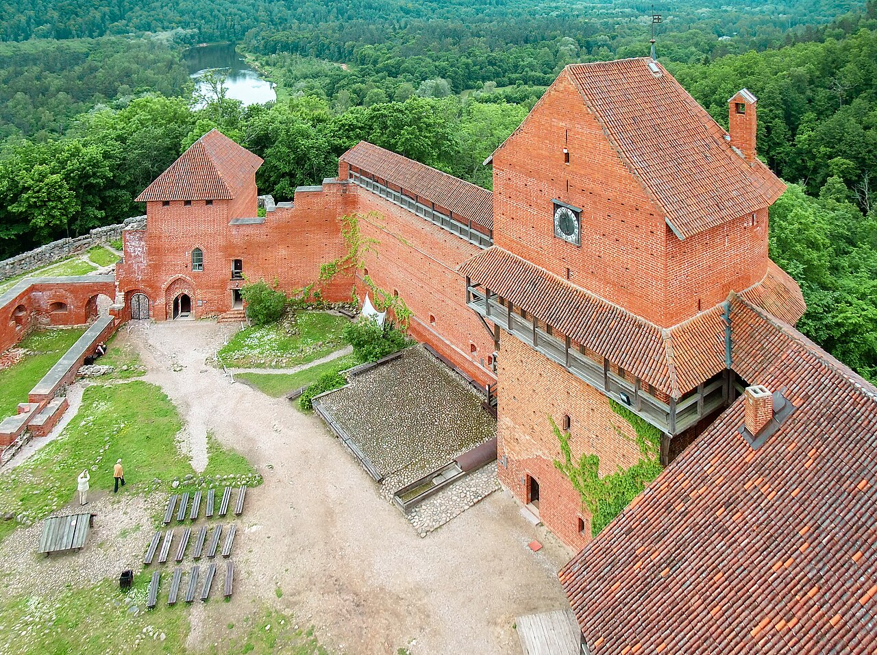 A tall red brick castle standing in the forests of Latvia.