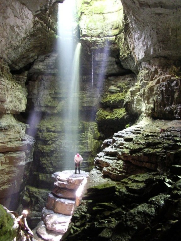 Explorers squeeze through a dark cave deep underground.