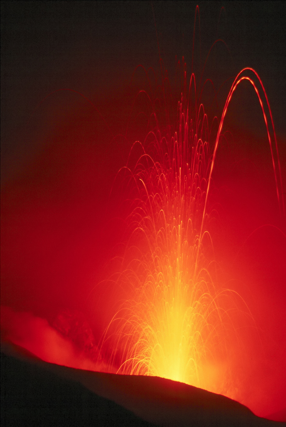 Glowing lava shoots high into the air from an erupting volcano.