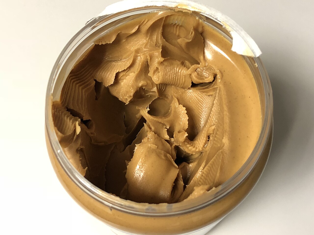 An open jar of smooth, creamy peanut butter.