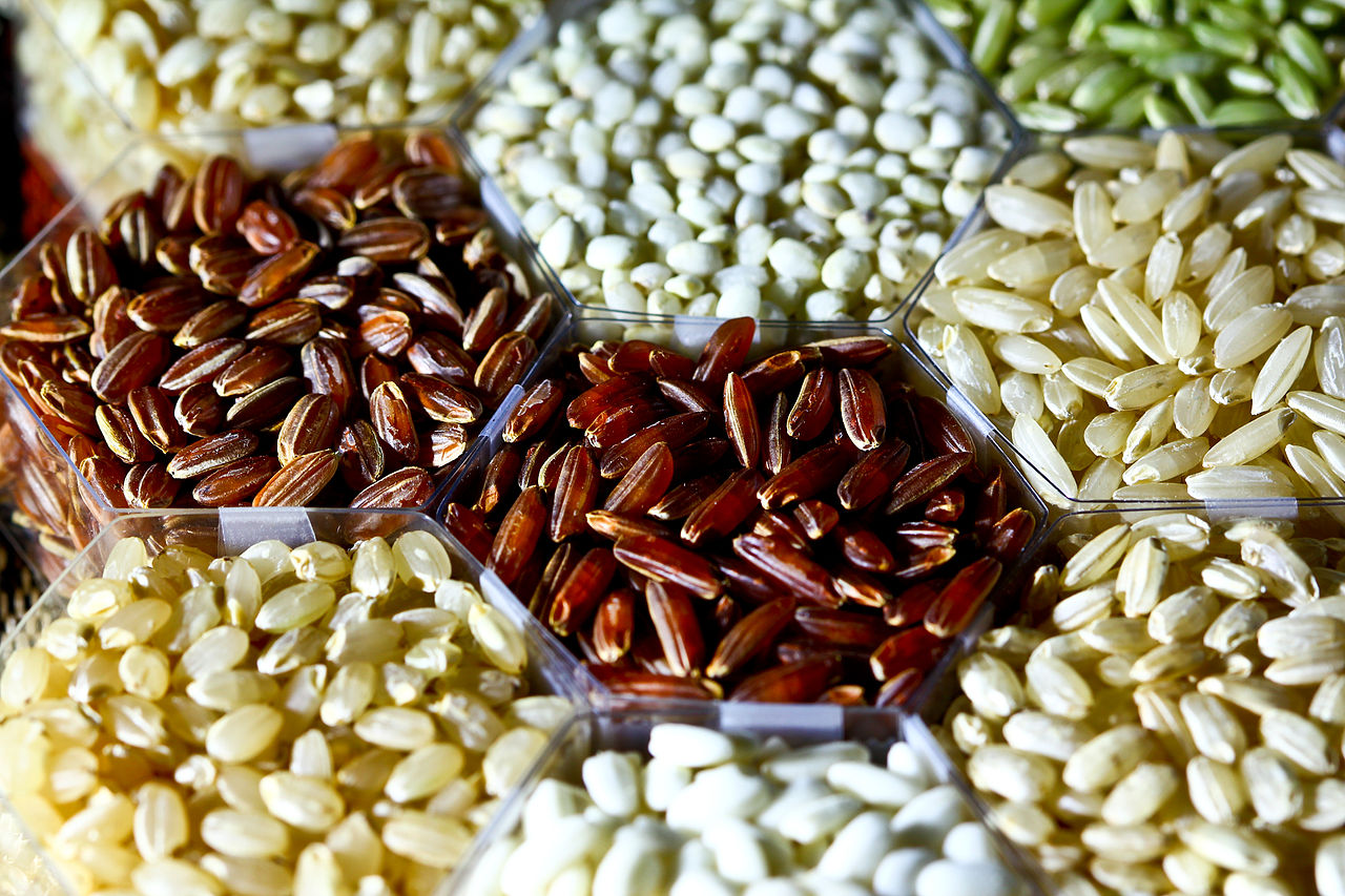 Many different kinds of colorful rice grains in small piles.