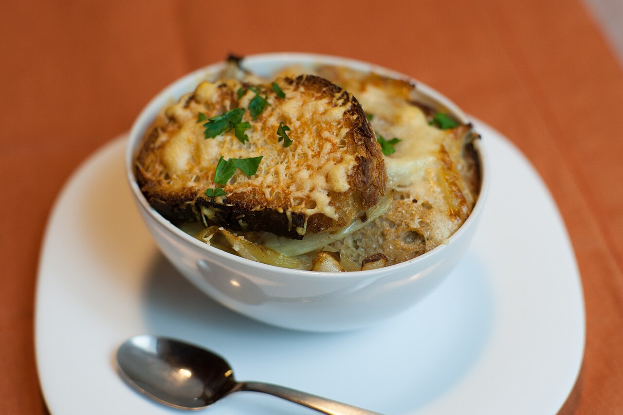 A warm bowl of onion soup with melted cheese on top.