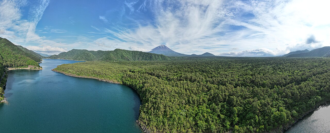 Mount Fuji stands tall behind a calm blue lake.