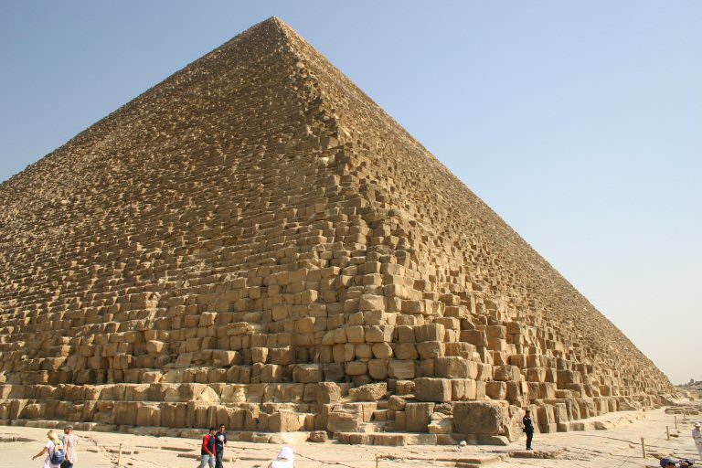 The Great Pyramid stands tall under a bright blue sky.