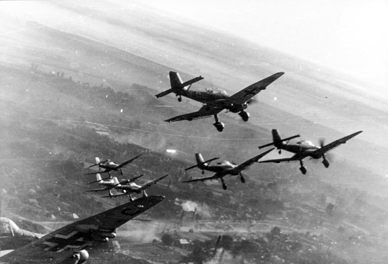 Warplanes fly high above a city during World War II.
