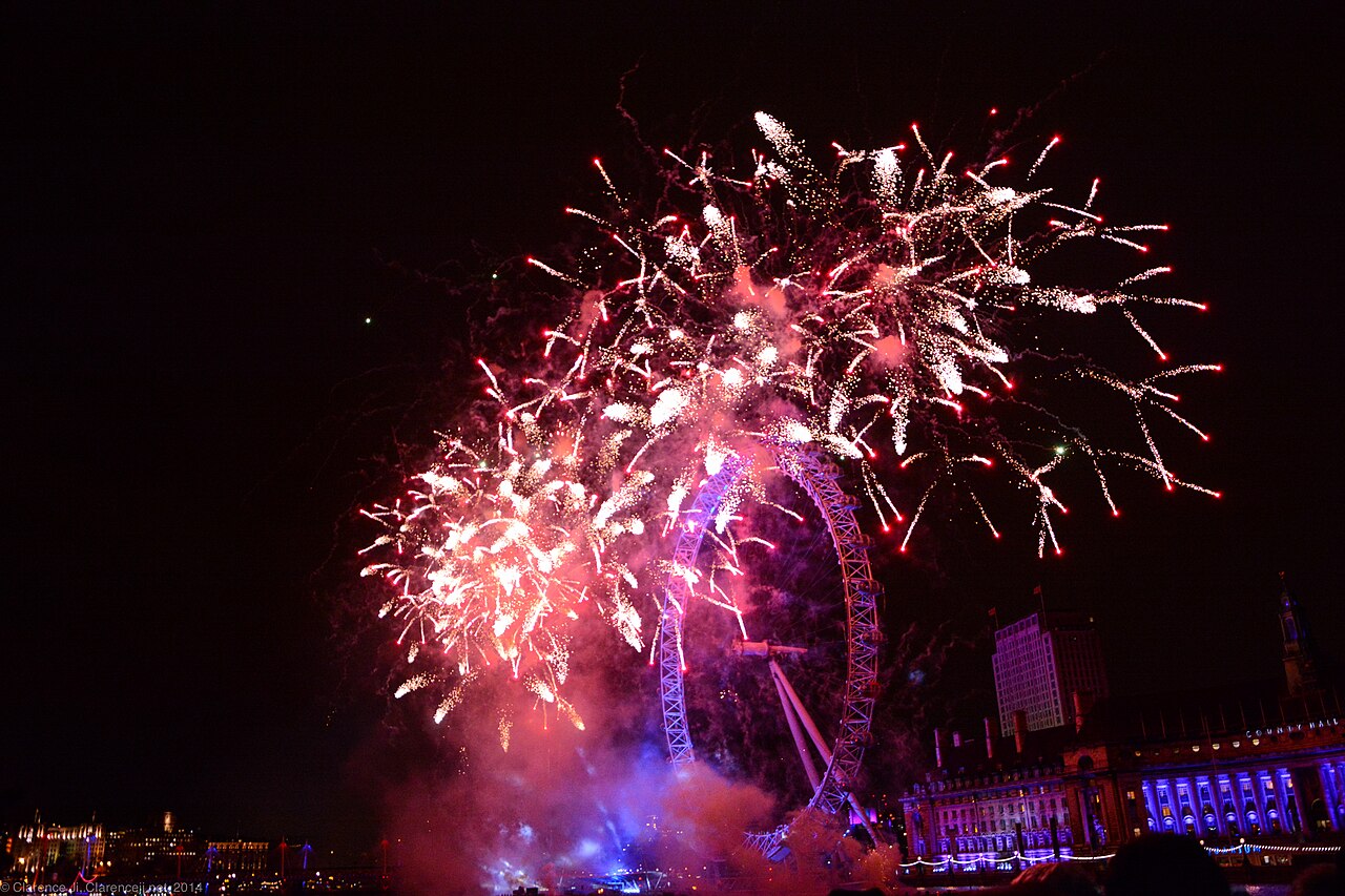 Bright fireworks sparkle over a giant Ferris wheel on New Year's Eve.