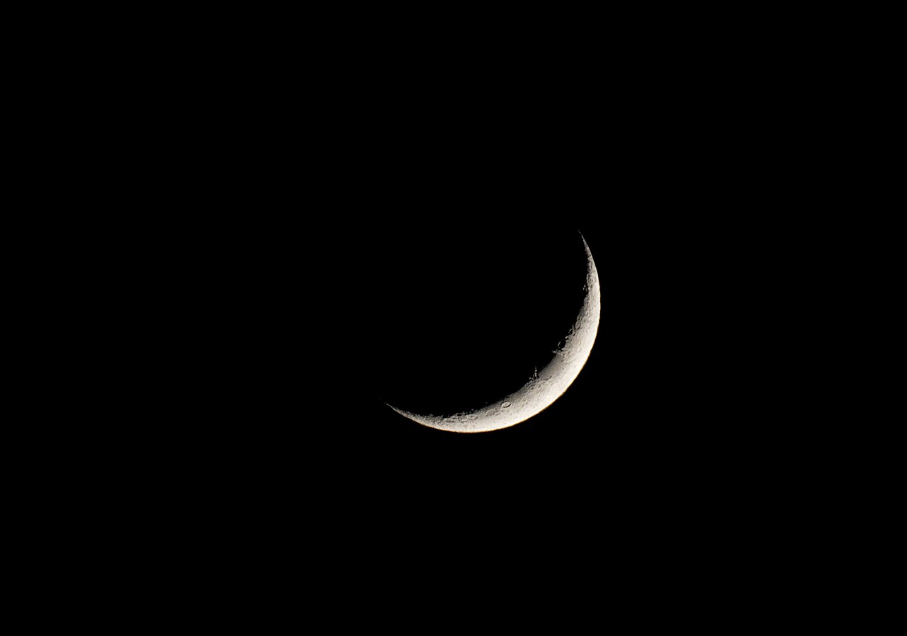 A thin crescent moon shines, marking the start of Ramadan.