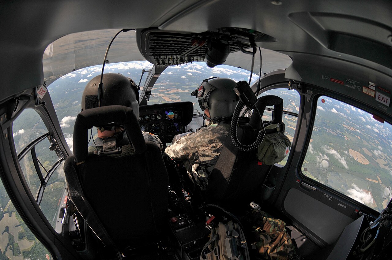 A helicopter flying high above a coastal town.