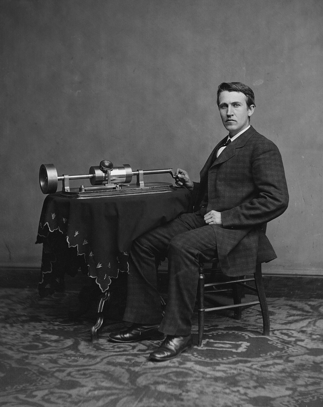 Thomas Edison sitting with his very first phonograph.