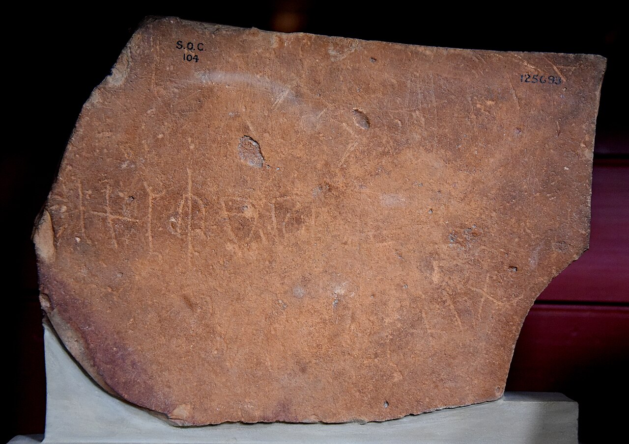An old red stone with early Arabic writing and a camel.