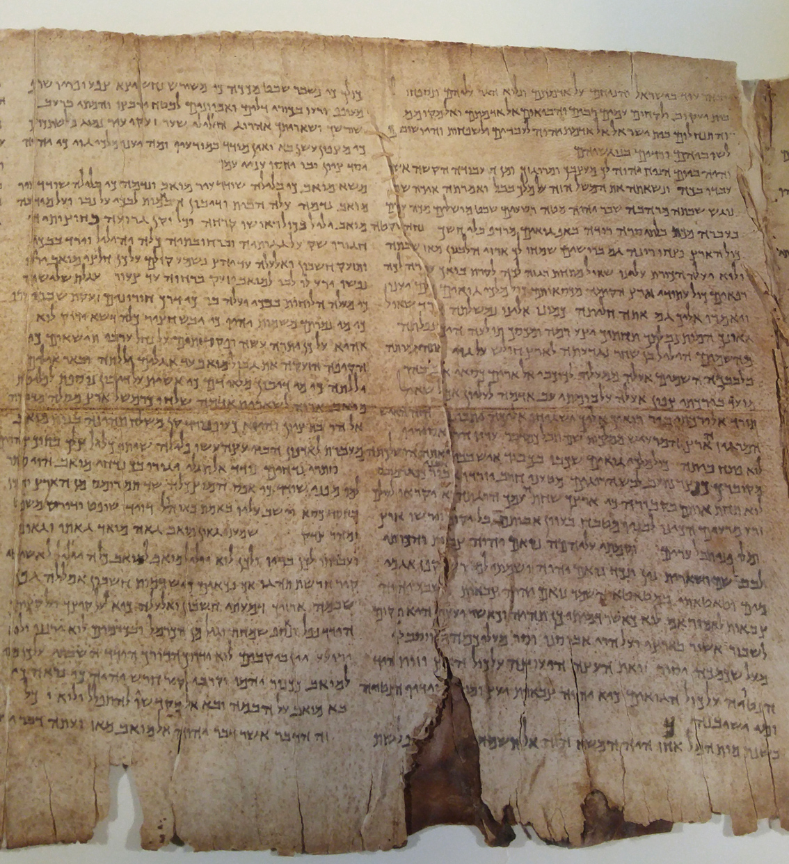 A very old Hebrew scroll with neat rows of writing.