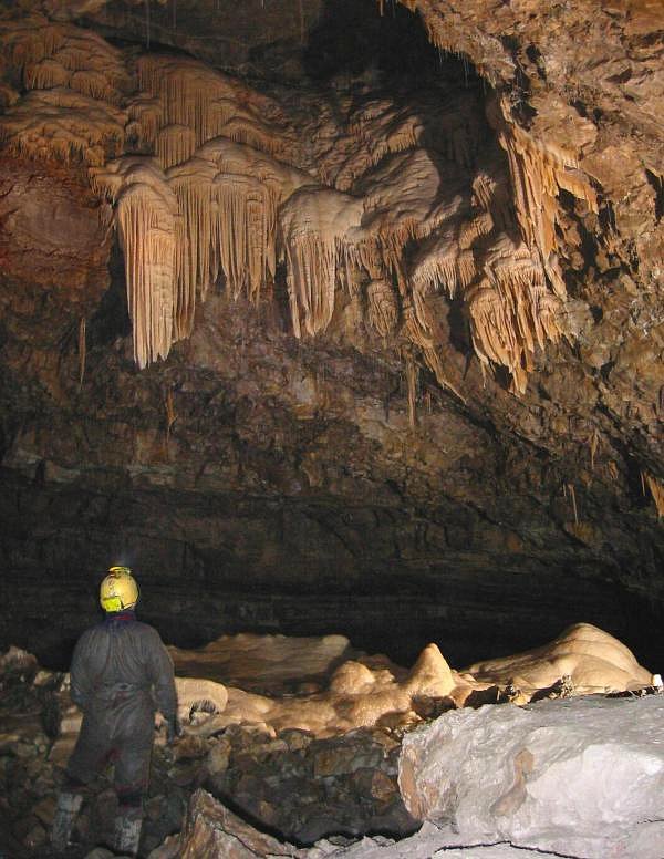 A huge cave chamber with tall rock walls.