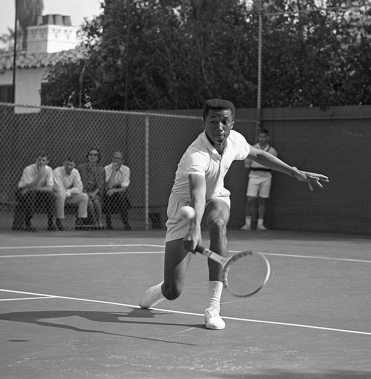 Young Arthur Ashe hitting a backhand in a 1964 tennis match.