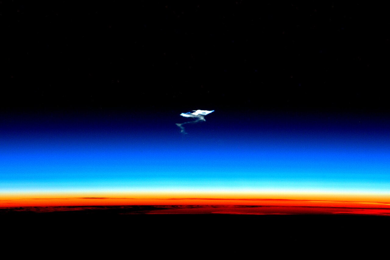 A space capsule glows as it zooms down through the air.