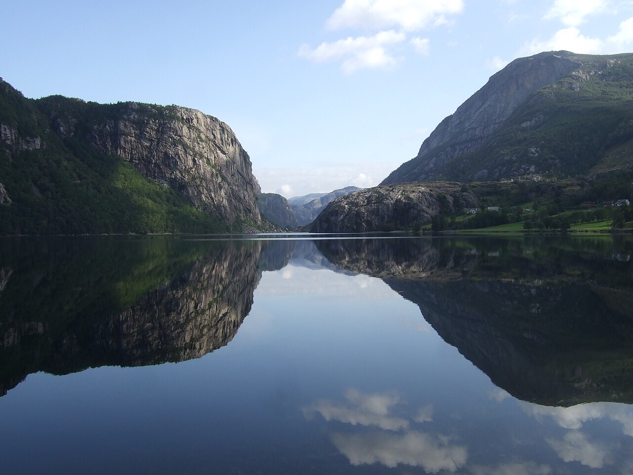 A calm icy lake rests between tall mountains in Norway.