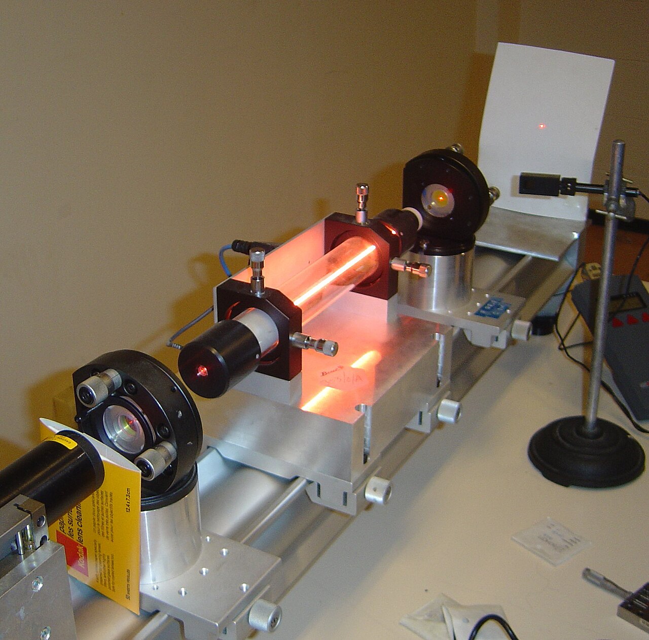 A bright red laser beam makes a glowing dot across a lab room.
