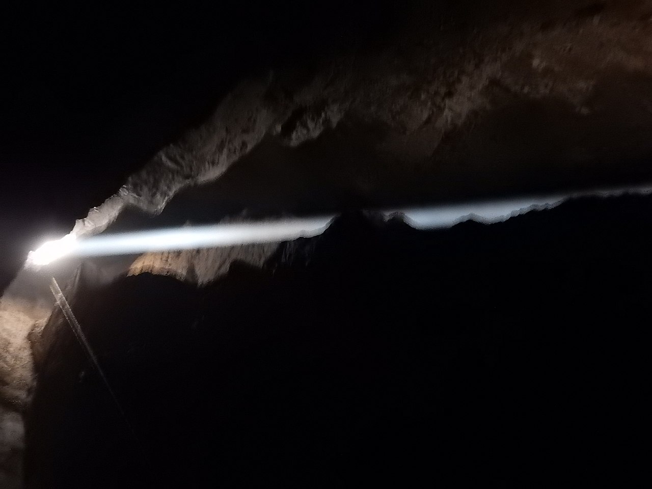 A golden sunbeam shines down into a dark rocky cave.
