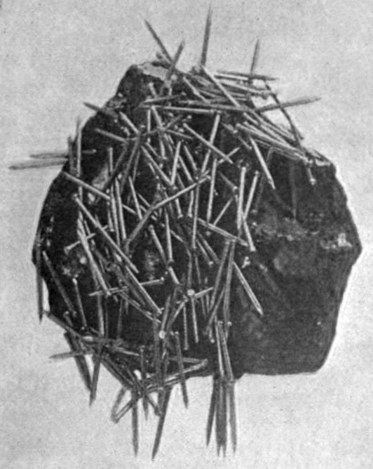 A natural magnet rock pulls iron nails toward itself.