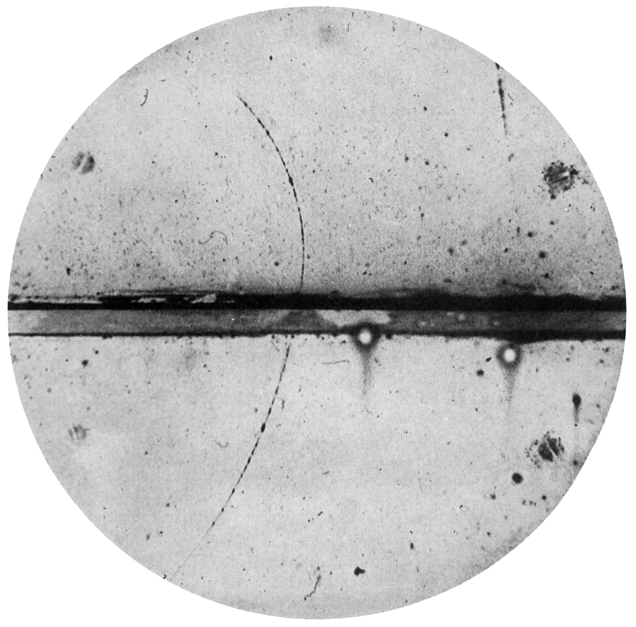 An old science photo showing a tiny particle's curved path.