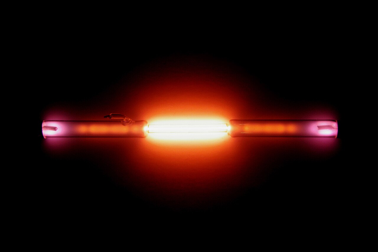 A glass tube filled with helium glows bright pink when powered.
