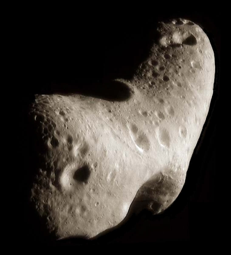 A close-up view of the bumpy, cratered surface of an asteroid in space.