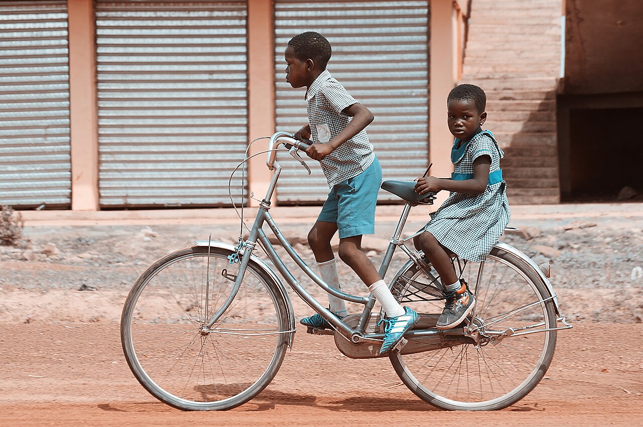 Cyclists pedal fast along a sunny road during a race.