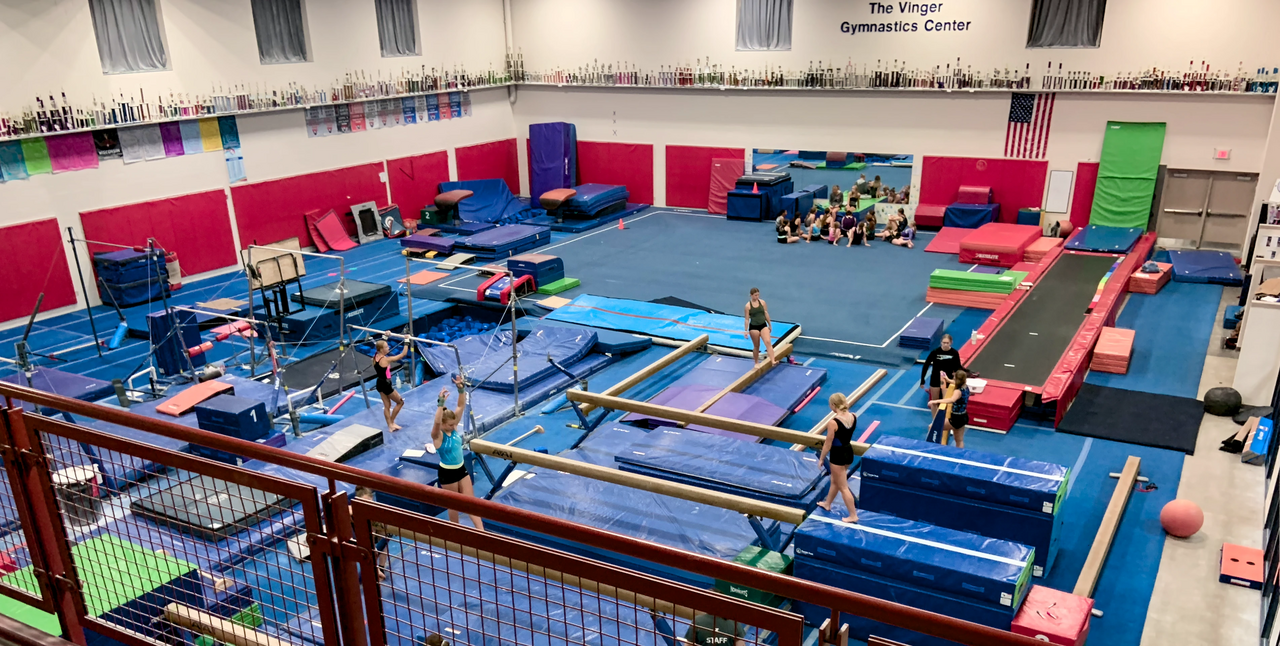 A gym filled with mats and bars where kids practice gymnastics.