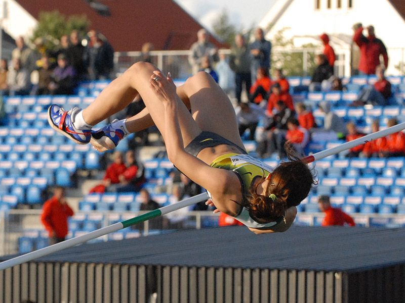 A high jumper arches her back to fly over the bar.
