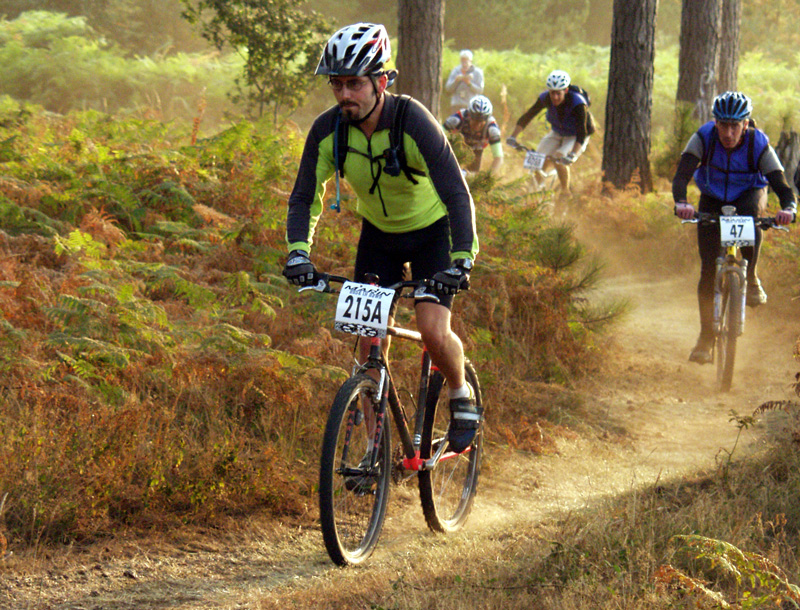 Mountain bikers race down a bumpy, rocky dirt trail.