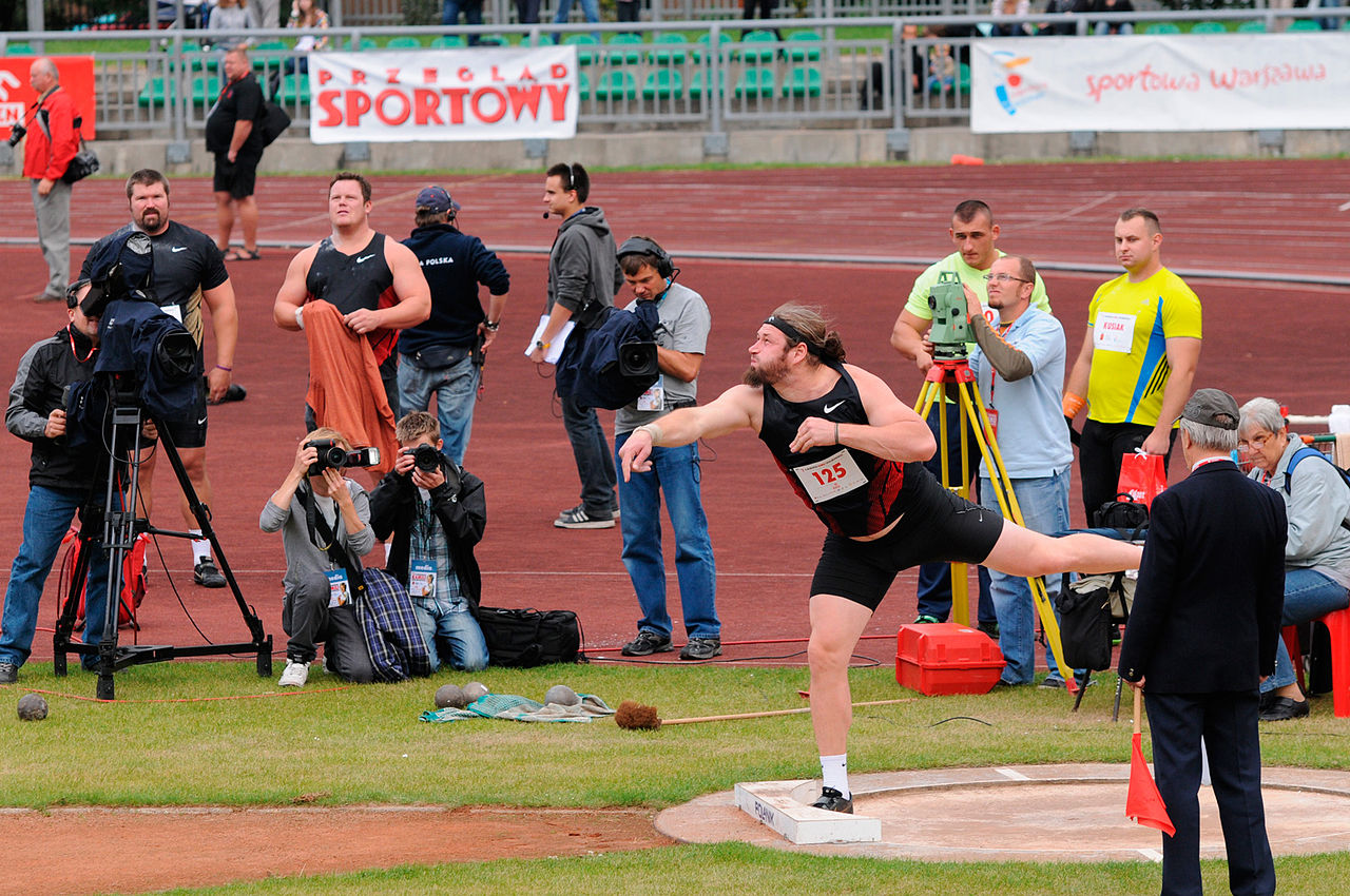 A strong athlete spins and pushes the heavy shot put ball.