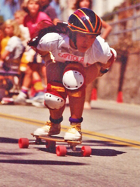 A skateboarder zooms down a hill in a fast race.