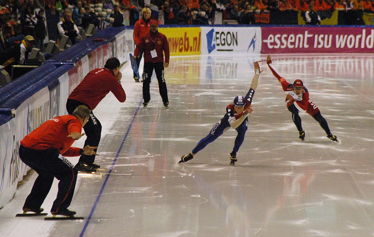 A speed skater leans forward and glides super fast on the ice.