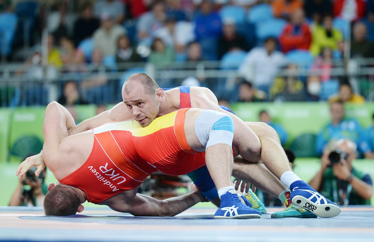 Two wrestlers grip and push as they fight for the win.